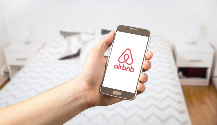person haelt smartphone mit airbnb app
