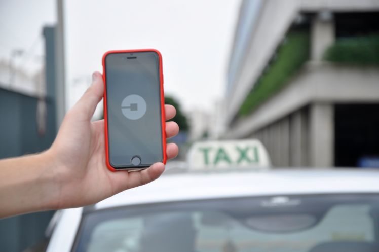 Smartphone mit taxi app wird vor taxi gehalten