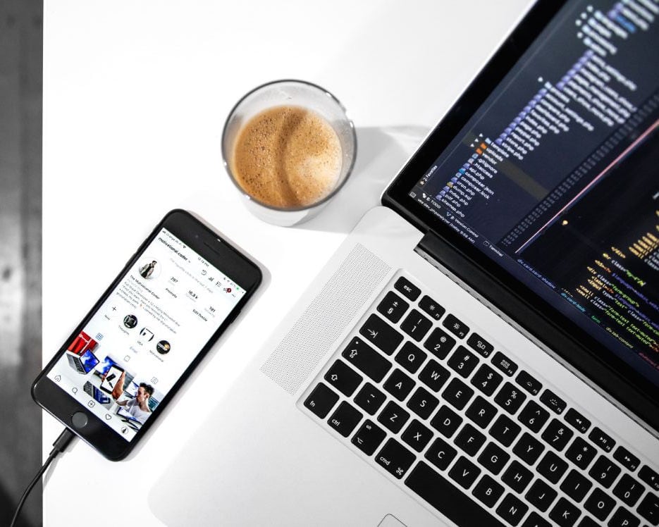 iphone liegt neben kaffee und macbook auf einem tisch