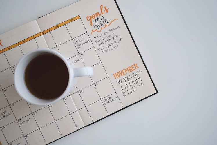 Kaffeetasse steht auf notebook mit Zielplanung