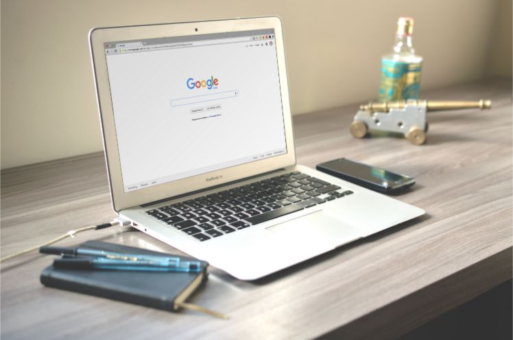 laptop auf Schreibtisch mit google suche offen
