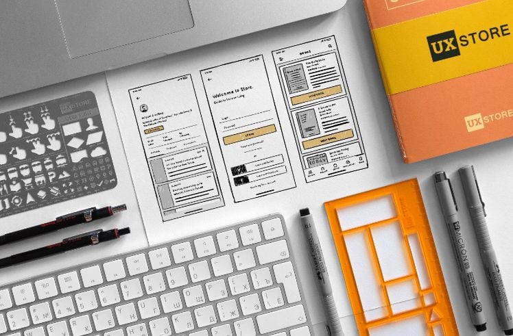 app wireframe sketches and office items laying on a desk app wireframe sketches and office items laying on a desk