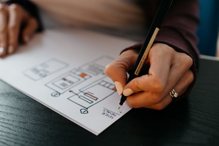 una mujer dibujando a mano alzada en un papel blanco wireframes de la app